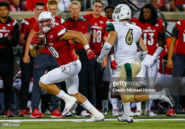 Cole Hikutini of the Louisville Cardinals runs the ball as Nick Cook of the Charlotte 49ers pursues at Papa John's Cardinal Stadium on September 1,...