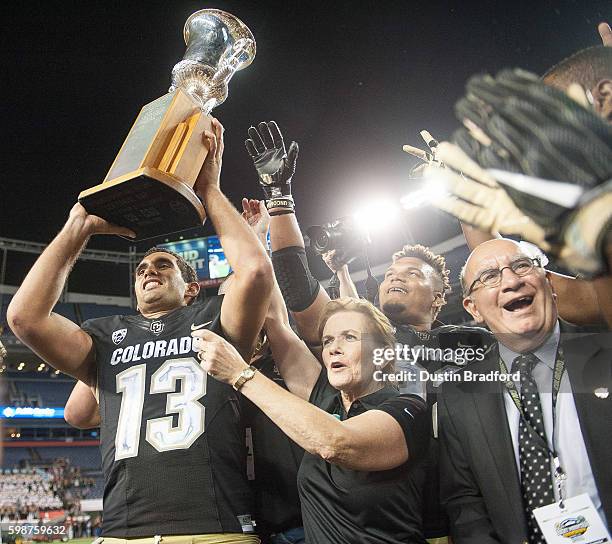 Quarterback Sefo Liufau of the Colorado Buffaloes hoists the Centennial Trophy after defeating the Colorado State Rams at Sports Authority Field at...