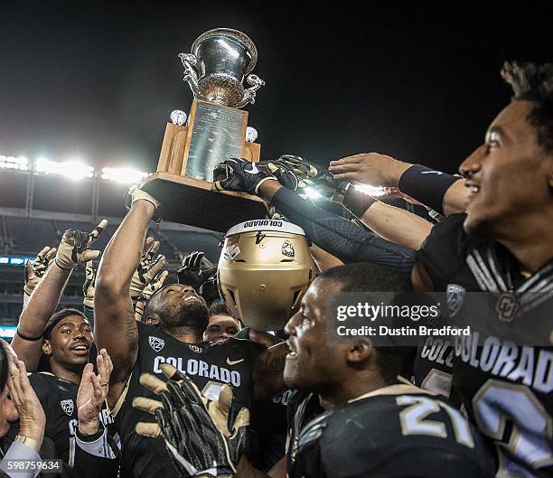 Colorado Buffaloes players celebrate as they hoist the Centennial Trophy after defeating the Colorado State Rams 44-7 at Sports Authority Field at...