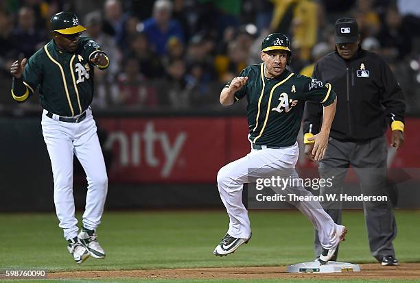 Danny Valencia of the Oakland Athletics rounds third to score waved home by third base coach Ron Washington against the Boston Red Sox in the bottom...