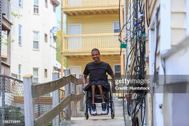 man in a wheelchair who had spinal meningitis on a ramp at his apartment building - acceso para sillas de ruedas fotografías e imágenes de stock