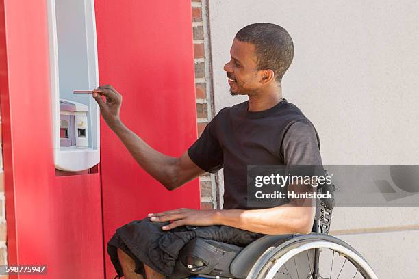 man in a wheelchair who had spinal meningitis using a bank atm - man atm smile stock pictures, royalty-free photos & images