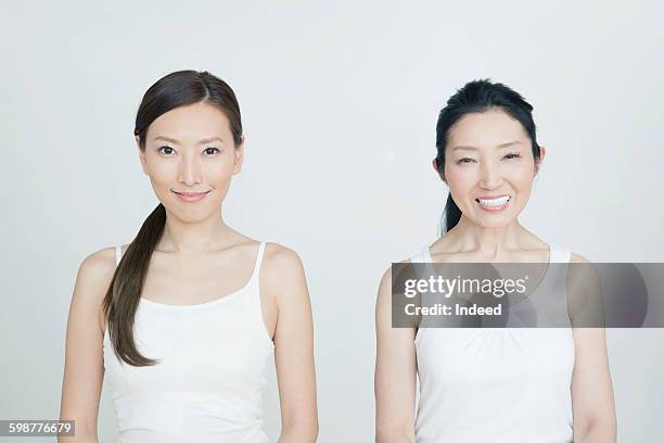 mother and daughter standing side by side - camiseta de tirantes fotografías e imágenes de stock