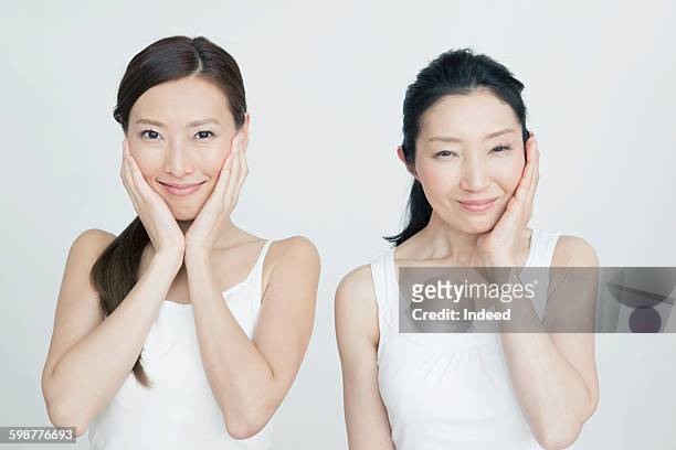 mother and daughter touching face - 若い女性 日本人 顔 ストックフォトと画像