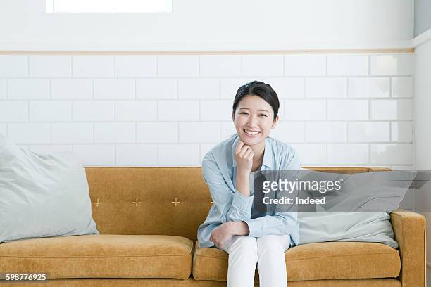 young woman sitting on sofa - living room front view stock pictures, royalty-free photos & images