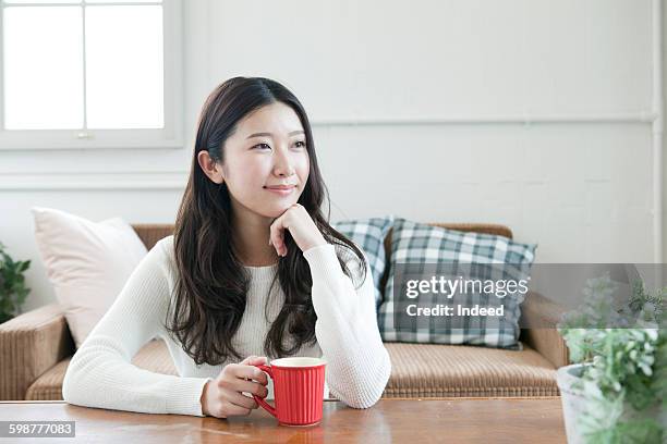 young woman relaxing in room - mano-en-la-barbilla fotografías e imágenes de stock