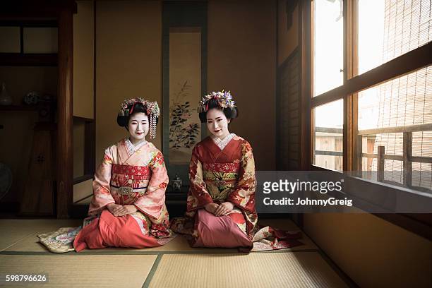 two japanese maiko kneeling on floor wearing kimonos - geisha japan stock pictures, royalty-free photos & images