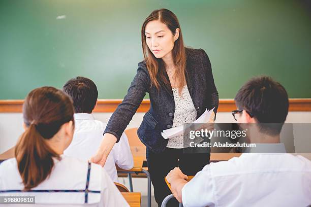 surveying teacher handing out exam papers, hong kong school, asia - giving back bildbanksfoton och bilder