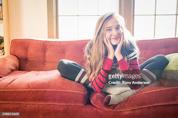 young woman siting on sofa at home - girls in leggings stock-fotos und bilder