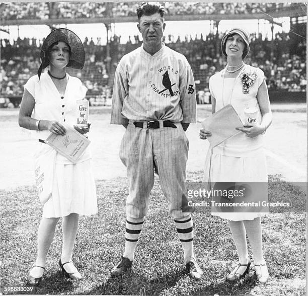Baseball player Grover Cleveland Alexander poses with two women, both of whom hold charity jars, before a game at Sportsmans Park, St Louis,...