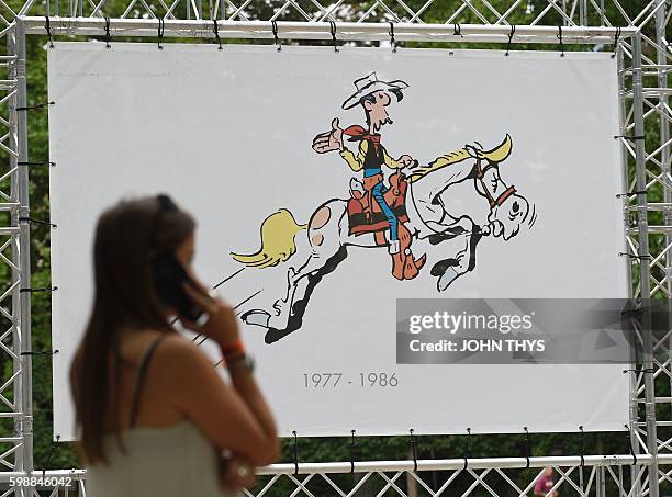 Women loopass by a Lucky Luke comic strip table during the festival "Fete de la BD" in Brussels, on September 2, 2016. The comic strip festival "Fete...