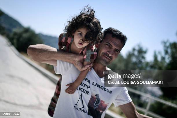 Ando Elias Tareq, 36 a Yezidi from Sinjar in Iraq holds his yougest daughter outside the Samos hotspot where they live on September 1, 2016. Tareq...