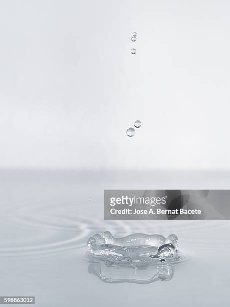 drops in a row on impact on a calm water supercie - slime stockfoto's en -beelden