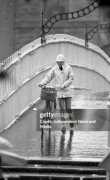 Dubliners cross the Ha' Penny Bridge soaked by the rains from Hurricane Charley, circa August 1986 .