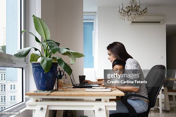 Woman working from a home office desk with her son