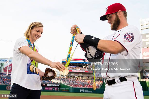 Katie Ledecky hands her Olympic medals to Bryce Harper of the Washington Nationals before throwing a ceremonial first pitch before the start of a MLB...