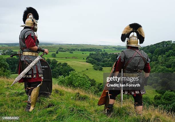 Roman soldiers stand guard looking out over the countryside of Cumbria from the Birdoswald Roman Fort as the lives of Roman Legionnaires are...