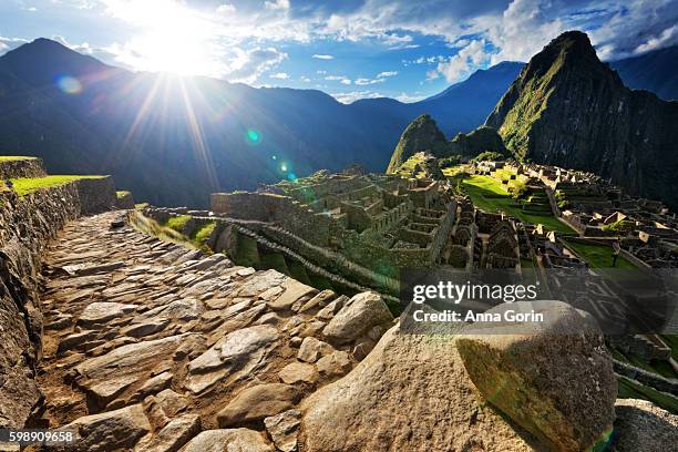 evening sunburst over deserted paved pathway overlooking machu picchu ruins, peru - machu picchu fotografías e imágenes de stock