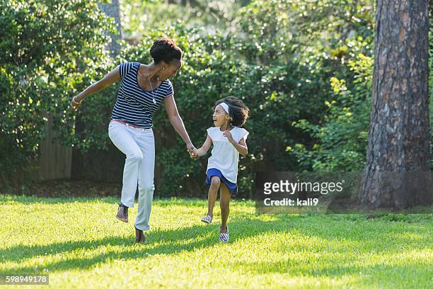 mère et fille afro-américaines sautant, riant - sautiller photos et images de collection