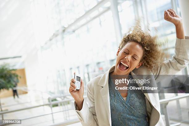 excited businesswoman holding cell phone - oliver eltinger stock pictures, royalty-free photos & images