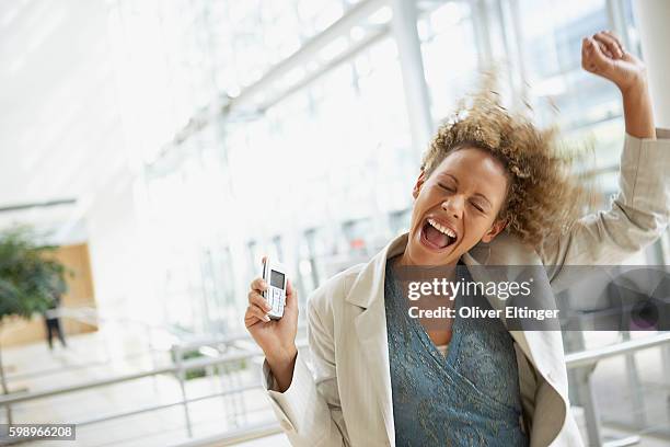 excited businesswoman holding cell phone - oliver eltinger - fotografias e filmes do acervo