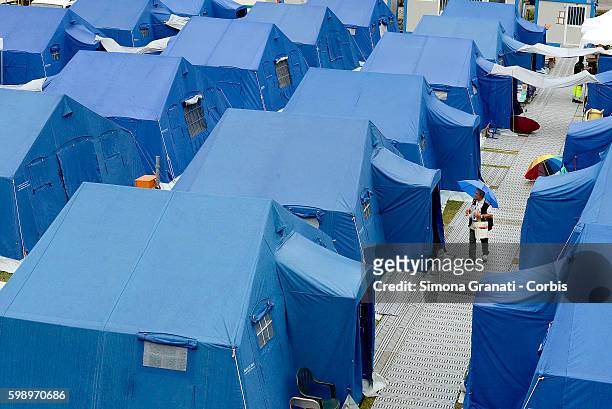 Man carrying an umbrella as he walks through the tent camp for earthquake victims ion August 31, 2016 in Arquata del Tronto, Italy. The region was...