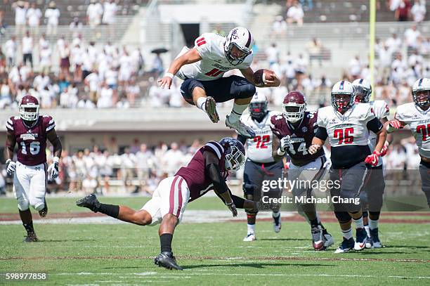 Quarterback Dallas Davis of the South Alabama Jaguars leaps over defensive back Brandon Bryant of the Mississippi State Bulldogs for a first down at...