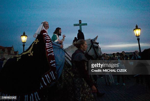 An actor representing King Charles IV and an actress representing Blanche of Valois, first wife of King Charles IV, ride on horses across the Charles...