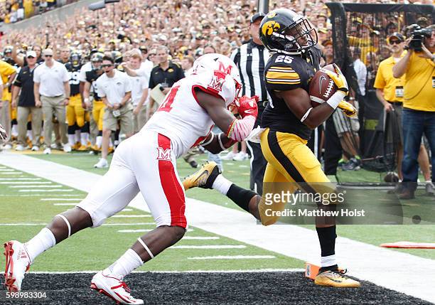 Running back Akrum Wadley of the Iowa Hawkeyes scores a touchdown during the first quarter in front of defensive back Tony Reid of the Miami RedHawks...