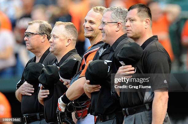 Caleb Joseph of the Baltimore Orioles and the umpire crew stand for the national anthem before the game against the New York Yankees at Oriole Park...