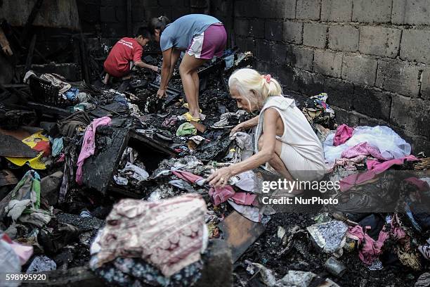 An elderly woman and her grandchildren salvage items from their burned house in suburban Quezon city, northeast of Manila, Philippines, April 6,...