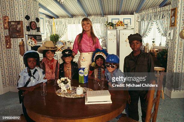 American actress Valerie Perrine surrounded by children dressed up as members of the disco band The Village People on the set of Can't Stop the...