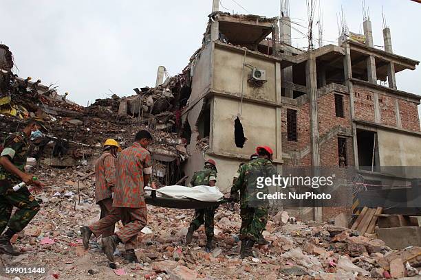 In this photograph taken on April 30 Rescue workers carry a body as they recover it from the debris of the damaged building at Savar, Dhaka...