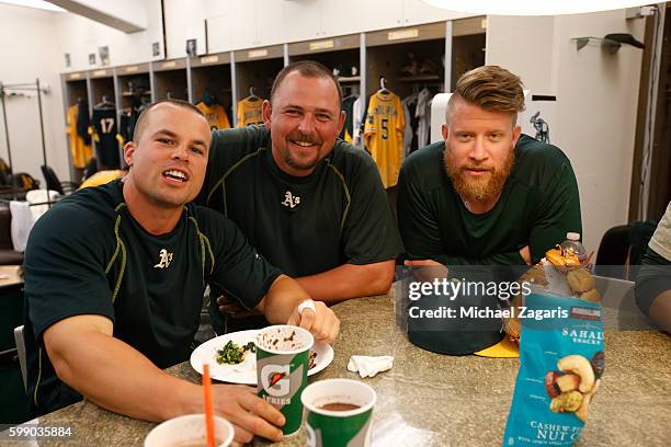 Jake Smolinski, Billy Butler and Sean Doolittle of the Oakland Athletics relax in the clubhouse prior to the game against the Baltimore Orioles at...