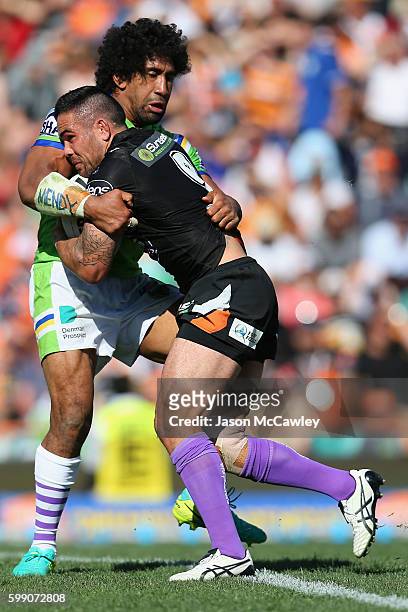 Dene Halatau of the Tigers is tackled by Iosia Soliola of the Raiders during the round 26 NRL match between the Wests Tigers and the Canberra Raiders...