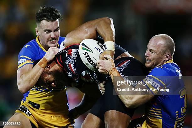 Manu Vatuvei of the Warriors is tackled by Clinton Gutherson and Beau Scott of the Eels during the round 26 NRL match between the New Zealand...