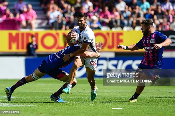 Clermont's Argentinan fly-half Patricio Fernandez is tackled by Stade Francais' Australian lock Hugh Pyle during the French Top 14 Rugby Union match...