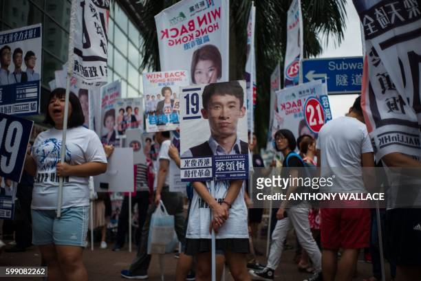 Campaigner stands behind a placard of Baggio Leung one of three candidates from new party Youngspiration, during the Legislative Council election in...