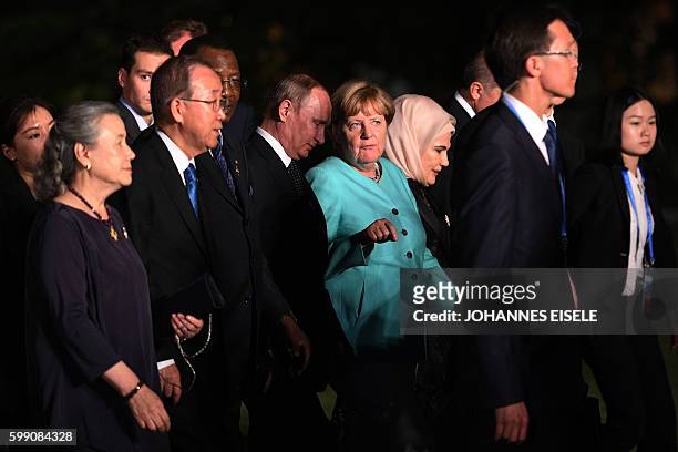 German Chancellor Angela Merkel talks to Russia's President Vladimir Putin as G20 leaders and their spouses walk for a group picture prior to a...