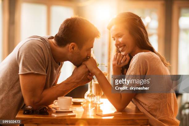 junge romantische mann küssen freundin die hand in einem café. - love woman stock-fotos und bilder