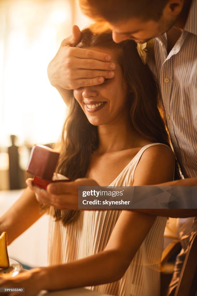 Young woman being surprised by her boyfriend with engagement ring.