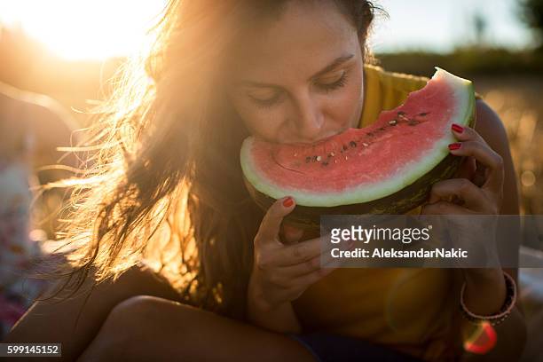 young woman eating watermelon outdoors - meloen stockfoto's en -beelden
