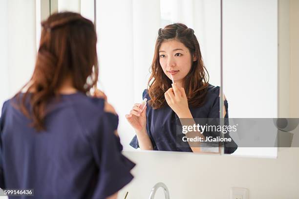 young woman putting on make up - woman long hair mirror stock pictures, royalty-free photos & images