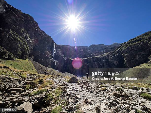 trekkers walking along the cirque of gavarnie . hautes pyrenees. france. world heritage by unesco, the great waterfall - midirock stock pictures, royalty-free photos & images