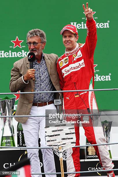 Sebastian Vettel of Germany and Ferrari waves to the crowd with Eddie Jordan on the podium during the Formula One Grand Prix of Italy at Autodromo di...