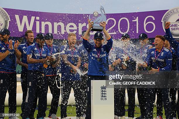 England captain Eoin Morgan raises the series trophy as his team-mates spray him with champagne at the end of play in the fifth one day international...