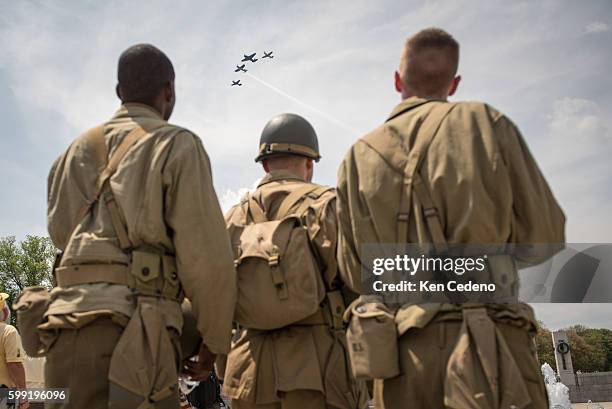 Reenactment soldiers from Ft. Myer watch as vintage WWII planes perform the "missing man formation," during a diverse array of World War II aircraft...