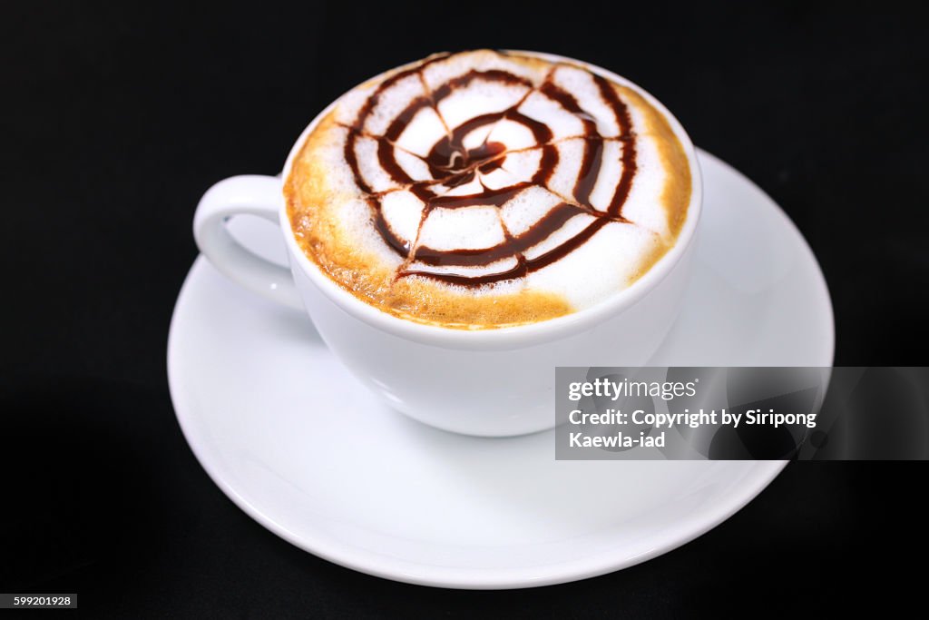 High angle view of a cup of coffee latte with cream and chocolate sauce.