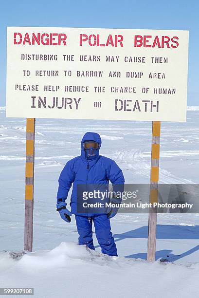 Man Wearing Arctic Clothing Under Polar Bear Warning Sign