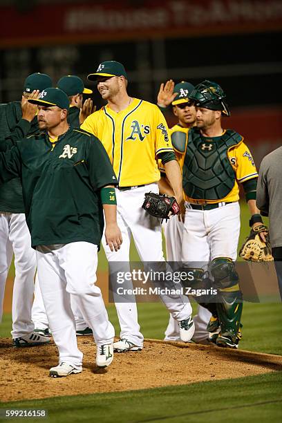 Billy Butler, Ryan Madson and Stephen Vogt of the Oakland Athletics celebrate with teammates on the field following the game against the Baltimore...